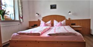 奥伯斯特多夫Landhaus Bergkristall - Sommer Bergbahnen inklusive的一间卧室配有一张带粉色床单和枕头的木床。