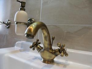 玛丽亚温泉爱丁堡酒店的浴室水槽配有黄铜水龙头和灯