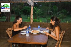 达瓦拉维Nil Bawana Nature Resort的两个坐在餐桌上吃食物的女人