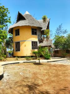蒙巴萨Kikambala Eco Villas的一座黄色房子,前面有一棵棕榈树