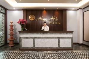 河内Nam Hai Hotel的酒店大堂的手机上的一个男人