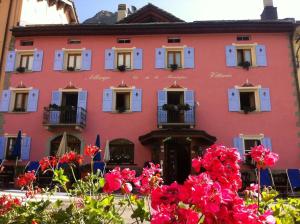 MontesplugaHotel Vittoria - Ca' De La Montagna的粉红色的建筑,有白色的窗户和鲜花