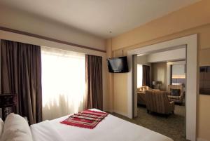 关丹Shahzan Hotel Kuantan, Trademark Collection by Wyndham的酒店客房配有一张带镜子的床和电视。