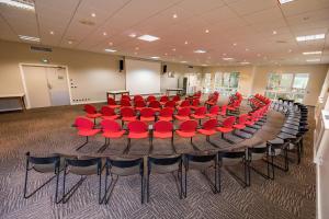 韦尔南图瓦Golf Domaine Du Val De Sorne的一间会议室,配有大桌子和红色椅子