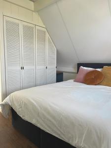 IlpendamDe hoftuin Ilpendam appartement的卧室配有一张白色大床和白色橱柜。