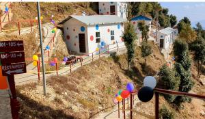 卡纳塔尔Dev Bhoomi Resort的山上的玩具屋,有街道标志和气球