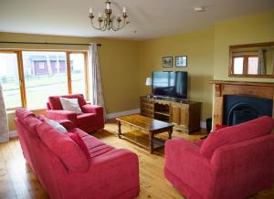 丁格尔Dingle Courtyard Holiday Homes 3 Bed的客厅配有2把红色椅子和电视