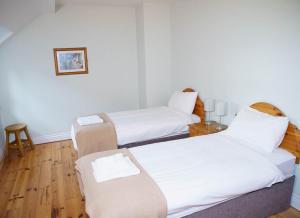丁格尔Dingle Courtyard Holiday Homes 3 Bed的配有白色床单和木地板的客房内的两张床