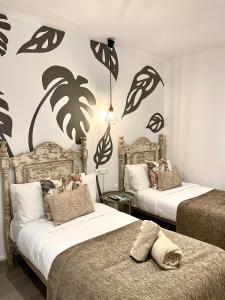 马贝拉Hostal El Caprichito Marbella的墙上棕榈树间内的两张床