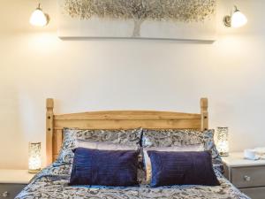 霍姆弗斯Weavers Cottage的一间卧室配有一张带两个蓝色枕头的木床