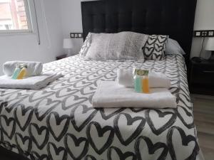 希洪Apartamento GIJON LOS CAMPOS的一张带两条毛巾和两杯饮料的床