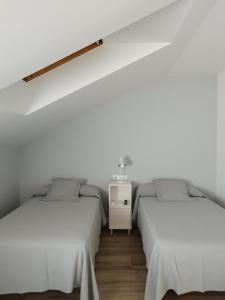 欧德鲁佐Pensión Residencial Platas的配有白色墙壁和木地板的客房内的两张床