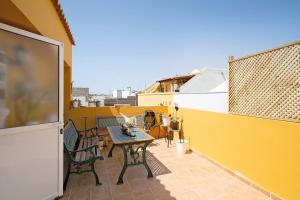 Castillo del RomeralCasa Las Caracolas的阳台设有一张黄色墙壁上的桌椅