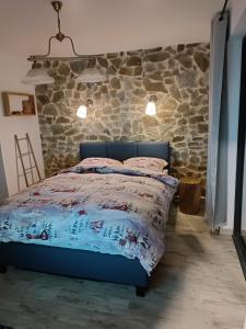 科利比塔Cabana de pe Stanca的卧室在石墙前配有蓝色的床