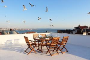 伊斯坦布尔Cihangir VAV Suites的屋顶上的桌椅,鸟儿飞过头顶