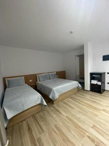 Rinas瓦萨奇酒店的一间卧室设有两张床,铺有木地板