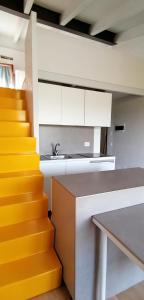 ValdirameLOGHINO Lombardo的厨房配有白色橱柜和黄色楼梯