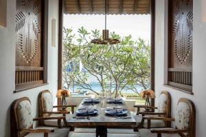 尼甘布Wattura Resort & Spa的一间带桌椅和窗户的用餐室