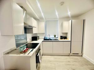 赫默尔亨普斯特德Hemel Apartments - Sea Breeze的白色的厨房配有白色橱柜和电器