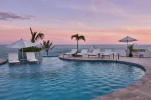 百慕大Azura Bermuda的度假村的游泳池,配有椅子和遮阳伞