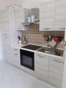 卡萨马塞拉Casa Vacanze Manin的厨房配有白色橱柜和水槽