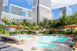 迈阿密EAST Miami Residences的一个带椅子和遮阳伞的游泳池以及建筑