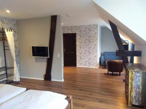 NeudorfDas Gartenhaus的一间带一张床和电视的卧室以及一间带楼梯的房间