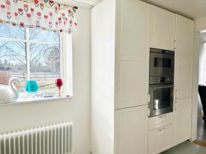 博尔斯塔Nice holiday home in Balsta的厨房配有白色橱柜和窗户。