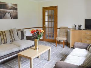 KiltarltyNursery Cottage - Beaufort Estate的客厅设有两张沙发和一张鲜花桌