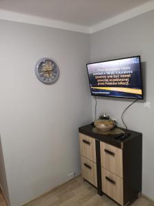 克罗斯诺Apartament przy dworcu的配有电视和墙上的时钟的房间