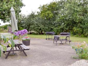 GoxhillCowslip Cottage- W43122的一组野餐桌、雨伞和鲜花