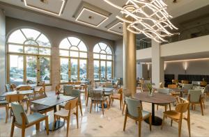 雷夫卡达镇莱夫卡斯酒店的一间带桌椅和吊灯的餐厅