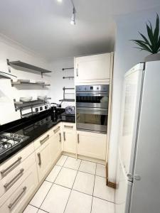 SurbitonBeautiful 2 bedroom garden flat w/ free parking的厨房配有白色橱柜和不锈钢冰箱