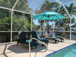 珊瑚角Villa Cosima的游泳池旁的游泳池配有椅子和遮阳伞
