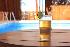 卡塔赫纳Cabaña Yalis SAS的坐在游泳池畔的桌子上喝杯啤酒