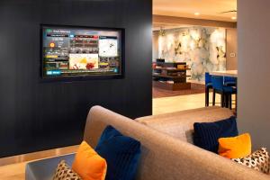 卡温顿辛辛那提科文顿万怡酒店的客厅配有沙发和墙上的电视