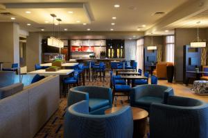 布卢明顿Courtyard by Marriott Bloomington的一间设有蓝色桌椅的餐厅和一间酒吧