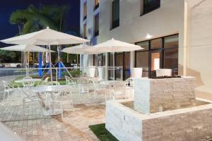 奥兰多万豪三角洲奥兰多酒店 - 布纳维斯塔湖的庭院配有白色的桌椅和遮阳伞。