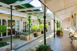 斯泰伦博斯Protea Hotel by Marriott Dorpshuis & Spa Stellenbosch的户外庭院设有桌子、长椅和植物