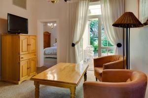 斯泰伦博斯Protea Hotel by Marriott Dorpshuis & Spa Stellenbosch的客厅配有桌椅和电视。