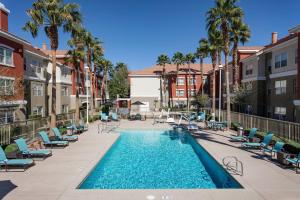 拉斯维加斯万豪Residence Inn拉斯维加斯亨德森/格林山谷酒店的一座带椅子和棕榈树的游泳池以及建筑