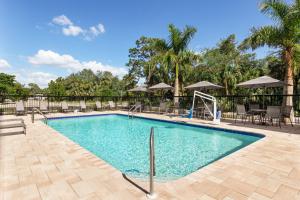 博尼塔斯普林斯Fairfield by Marriott Inn & Suites Bonita Springs的度假村的游泳池,配有椅子和遮阳伞