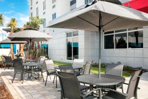 代托纳海滩Fairfield Inn & Suites by Marriott Daytona Beach Speedway/Airport的一个带桌椅和遮阳伞的户外庭院。