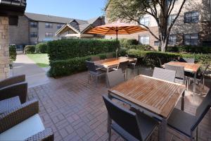 普莱诺Residence Inn by Marriott Dallas Plano/Legacy的一个带桌椅和遮阳伞的庭院