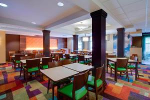 克莱蒙Fairfield Inn & Suites by Marriott Clermont的用餐室配有桌子和绿色椅子