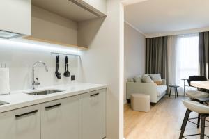 多特蒙德Residence Inn by Marriott Dortmund City的一间带水槽的白色厨房和一个客厅