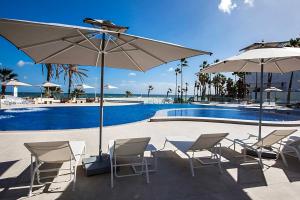 苏塞Sousse Pearl Marriott Resort & Spa的一组椅子和遮阳伞,位于游泳池旁