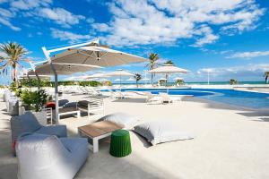 苏塞Sousse Pearl Marriott Resort & Spa的一个带椅子和遮阳伞的庭院和一个游泳池