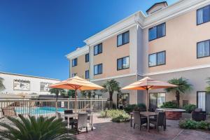伯锡尔城什里夫波特博西尔市/路易斯安那州布劳德沃克万怡酒店的酒店庭院设有桌子和遮阳伞,还有一个游泳池。