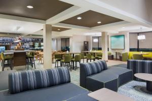 斯普林菲尔德Courtyard by Marriott Springfield Airport的酒店大堂设有桌椅和酒吧
